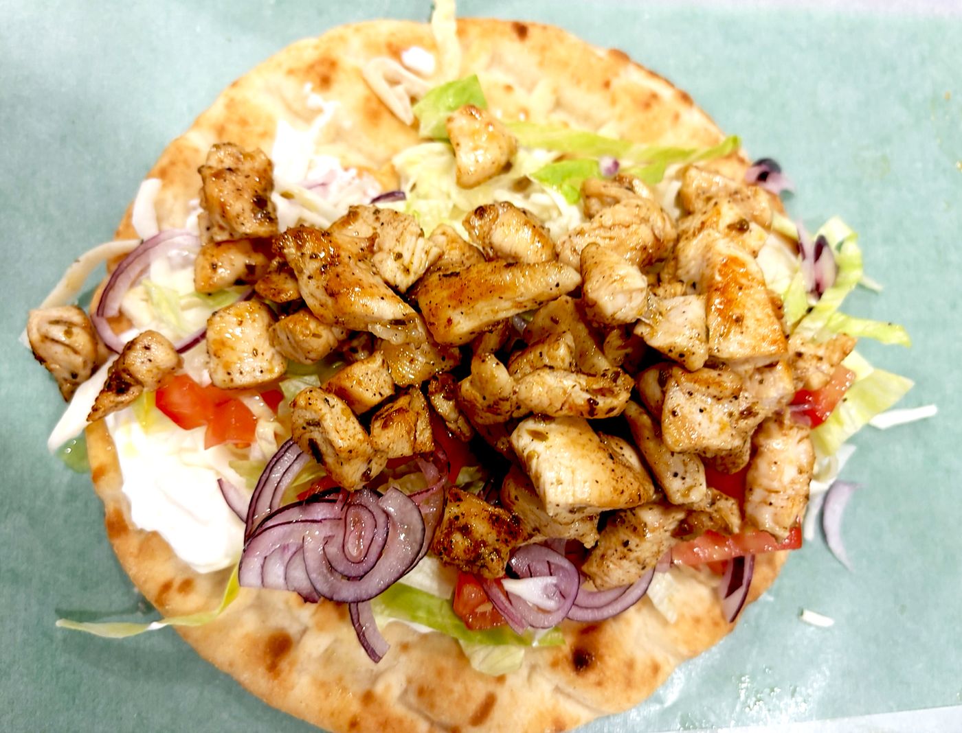 Pita souvlaki de poulet ouverte : poulet grillé, oignon rouge, tomate et sauce